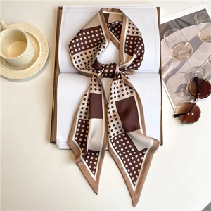 Close-up of a polka dot and geometric pattern skinny silk scarf on lifestyle props