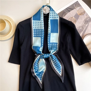 Close-up of polka dot silk scarf tied on a sweater with a white camellia flower brooch