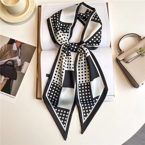 Detailed view of polka dot satin skinny scarf styled with a classic beige handbag
