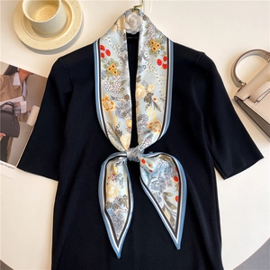Detail of floral skinny silk scarf tied on a black sweater with lifestyle background