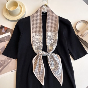 Detailed flat lay of a paisley and houndstooth silk scarf with lifestyle accessories
