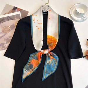 Close-up of a floral silk scarf styled on a black knit top with a coffee lifestyle setup