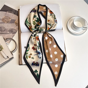 Close-up of floral and polka dot silk neck scarf with fine stitching on white desk