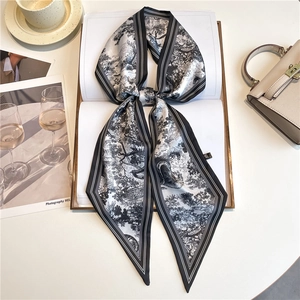 Detail shot of a black and white Toile de Jouy silk scarf tied in a bow on a book