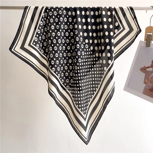 Detailed view of polka dot and letter print on black and white silk square scarf