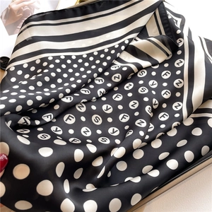 Detail view of the elegant satin silk scarf showing polka dots and letter print texture