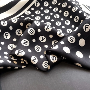 Detail of silk-like scarf with black and white polka dots and letter print texture