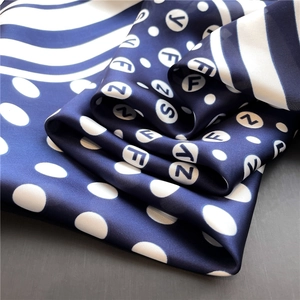 Detailed view of polka dots and stripes on a navy blue silk-like square scarf texture