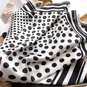 Close-up of black and white polka dot silk scarf with lettered patterns and soft folds