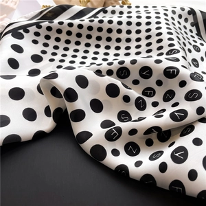 Detail of silk satin scarf showing black polka dots with letters and elegant drapes