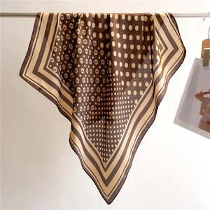 Detail of silk-feel square scarf with polka dots and stripes draped on a metal bar