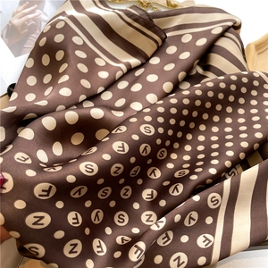 Detailed view of polka dot and stripe silk scarf texture with luxury letter patterns