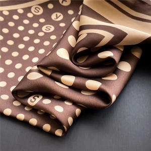Detailed close-up of brown and beige polka dot silk scarf with elegant satin luster