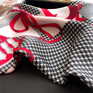 Close-up of houndstooth silk scarf with red patterns and fine stitched edges