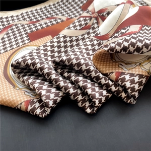 Macro detail of houndstooth silk scarf showing premium smooth texture and elegant patterns