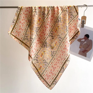 Detail of floral silk scarf with orange flowers and paisley patterns on a metal rod