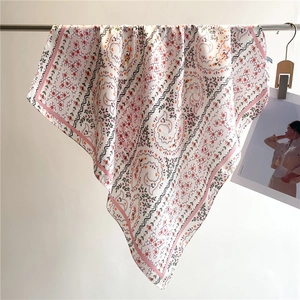 Floral square scarf in cream with pink wavy borders, elegantly draped on a metal bar