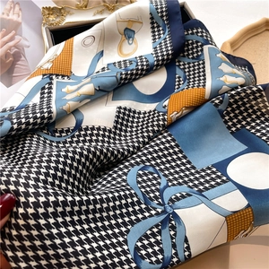 Detail of silk-feel scarf with houndstooth pattern and elegant bow bag illustrations