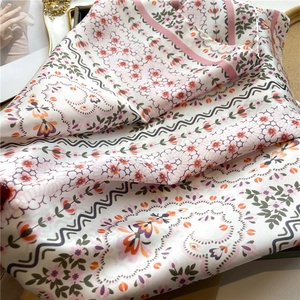 Close-up of floral print silk scarf with wavy borders and elegant fine stitched edges