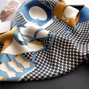 Detailed view of houndstooth silk scarf with elegant gold and blue geometric patterns