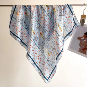 Detail of floral paisley pattern silk-feel square scarf hanging on a metal rod