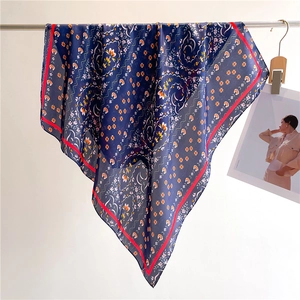 Close-up of floral print silk scarf in navy blue and orange with red border details
