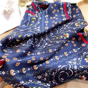 Detailed macro view of vintage floral silk scarf with glossy texture and navy patterns