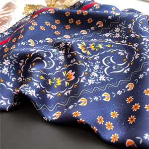 Detailed close-up of navy blue floral silk scarf showing soft texture and fine red hem