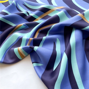 Detailed view of silk scarf fabric showing blue abstract waves and smooth texture