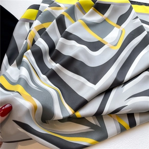 Detailed view showing the silky texture and abstract geometric pattern of the silk scarf