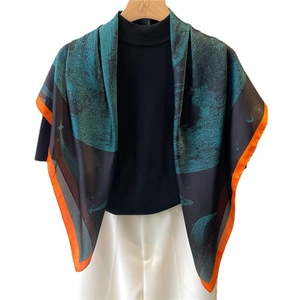 Carré de soie aux motifs célestes et bords roulés oranges sur un élégant blazer