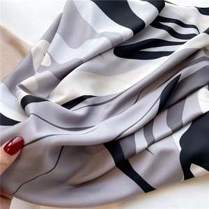 Close-up of luxury silk scarf showing abstract floral pattern and satin texture details