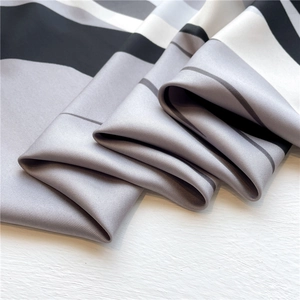 Detail of elegant silk scarf showing geometric striped patterns and premium twill texture