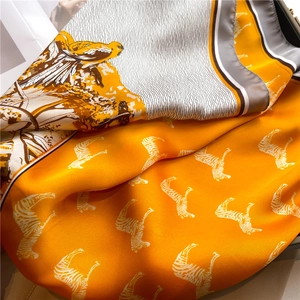 Close-up of silk scarf with orange and grey blocks, bird and zebra patterns