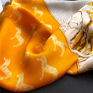Close-up of bright orange silk scarf featuring white zebra prints and jungle illustrations