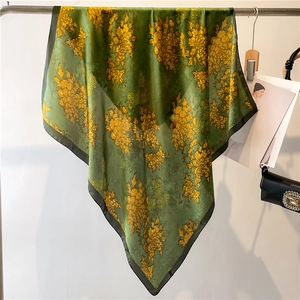 Green silk floral scarf featuring golden peonies and traditional patterns on a hanger