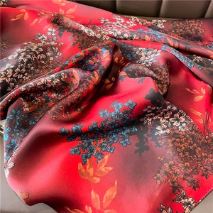 Detail of red floral silk scarf showing elegant folds and glossy satin texture finish