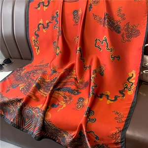 Detail of red silk scarf with phoenix and clouds pattern on a dark leather texture