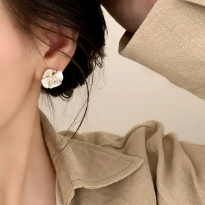 Elegant white petal flower earrings with gold trim and crystal, worn by a model