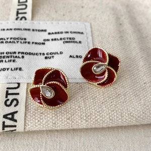 Detail of red enamel flower earrings with gold beaded edges and teardrop zircon center