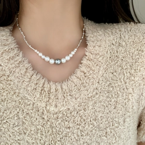 Collier de perles élégant avec perle grise sur mannequin en pull en maille beige