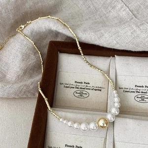 Détail d'un collier doré élégant avec perles dégradées exposé sur un support de luxe