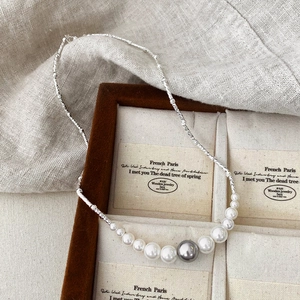 Détail d'un collier chaîne torsadée argentée avec perles dégradées sur support velours
