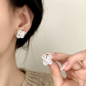 Elegant silver clover stud earrings with pearls shown on model and held by hand