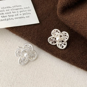 Detail shot of hollow flower earrings with white pearl and small crystals on knit background