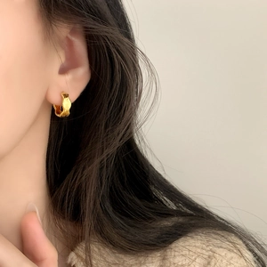 Minimalist gold textured hoop earrings with vertical wave pattern worn by female model
