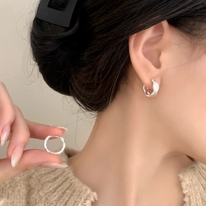Minimalist silver wavy textured hoop earrings worn by a model for a chic daily look
