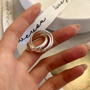 Minimalist silver interlocking triple-band rolling ring worn on a finger