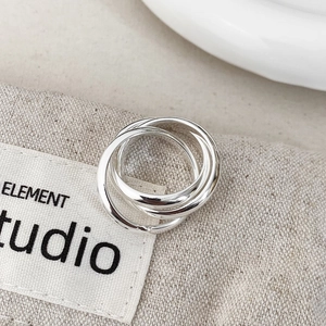 Close-up of minimalist layered interlocking silver rings on a textured linen background