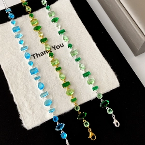 Elegant gold and silver bracelets with multicolored emerald-cut zircons on a gift card